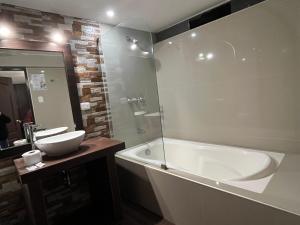 a bathroom with a tub and a sink and a mirror at La Estancia de la Abuela Cusco Hotel in Cusco