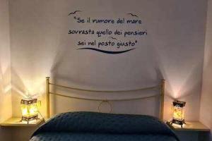 a bedroom with a bed with two lights and words on the wall at Villa Meridiana 2 - a due passi dal mare in Trappola