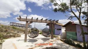 a playground with two swings in front of a building at Chale em Serra Negra com vista para montanha in Bezerros