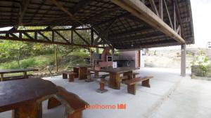 a group of picnic tables and benches under a roof at Chale em Serra Negra com vista para montanha in Bezerros