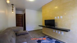 a living room with a couch and a flat screen tv at Chale em Serra Negra com vista para montanha in Bezerros