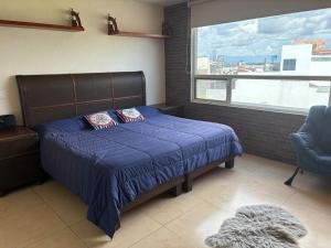 a bedroom with a bed with a blue comforter and a window at Luxurious house in Puebla in Tlazcalancingo