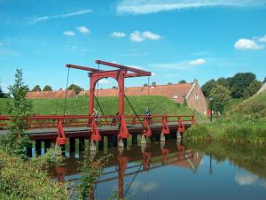 Eine rote Brücke über einen Fluss mit Leuten darauf. in der Unterkunft Zur Linde in Heede