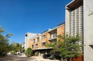 an apartment building with cars parked in front of it at 3BR Beachfront with Private Rooftop at Tankah Bay in Tulum