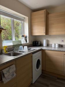 a kitchen with a sink and a washing machine at Quiet Yellow Rest House Sleeps 7 in Swindon