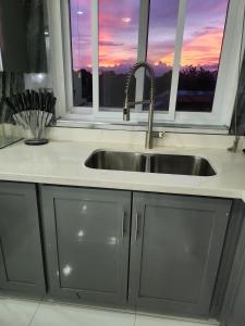 a kitchen sink in front of a window with a sunset at Modern Kingston Condo with Rooftop Pool and View in Kingston