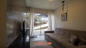 a living room with a couch and a large window at Chale em Serra Negra vista para montanha e lareira in Bezerros