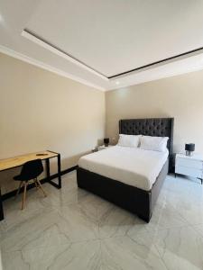 a bedroom with a bed and a table and a desk at Palms & Pebbles Lodge in Lilongwe