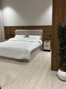 a bedroom with a white bed and a potted plant at شقة غرفة وصاله - حي البرج in Al Kharj