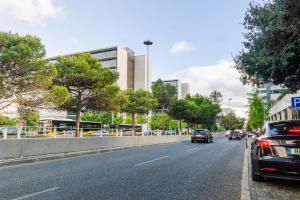 a street with cars driving down a road with buildings at Charmoso Mirante in Lisbon