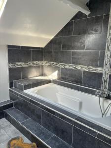 a bath tub in a bathroom with black tiles at Maison moderne avec jardin espace télétravail in Bobigny +24 photos