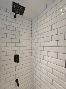 a bathroom with white tiled walls and a shower at Evara - stay explore belong in Varanasi