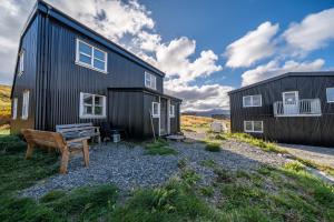 a black house with a bench in front of it at Dis Cottages in Grundarfjordur