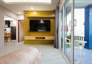 a living room with a tv on a yellow wall at Luxury New Villa 2BR Pool near Bangtao Laguna and Beach in Ban Thalat Choeng Thale