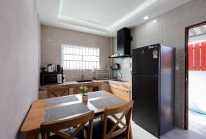 a kitchen with a table and a black refrigerator at Luxury New Villa 2BR Pool near Bangtao Laguna and Beach in Ban Thalat Choeng Thale