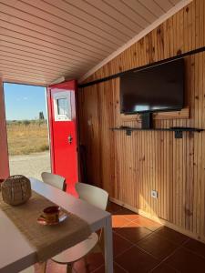Habitación con mesa, TV y puerta roja. en Cantinho Alentejano, en Oriola