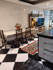 a dining room with a table and chairs and a checkerboard floor at Casa do aconchego k&P in Paraty