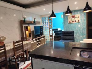 a kitchen and living room with a counter and a tv at Casa do aconchego k&P in Paraty