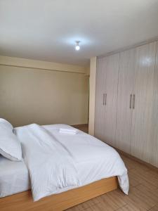 a bedroom with a large white bed and wooden cabinets at The Hideout, juja in Juja +5 photos