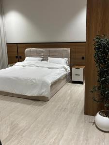 a bedroom with a white bed and a potted plant at شقة جديدة بغرفة وصالة in Al Kharj