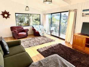 a living room with a couch chair and a television at Sandy Beach Apartment in Russell