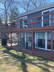 eine große Terrasse mit Stühlen und Tischen auf einem Haus in der Unterkunft Year-round Cozy Cottage Charm on Cayuga Lake in Romulus