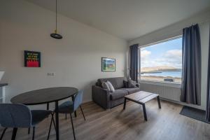 a living room with a table and a couch and a window at Hafnir in Grundarfjordur