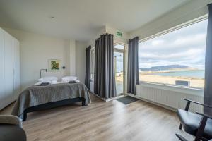 a bedroom with a bed and a view of the beach at Hafnir in Grundarfjordur