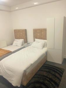 a bedroom with two beds with white sheets at studio apartment with small kitchen and bathroom in Colne