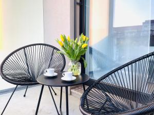 une table avec deux chaises et un vase avec des fleurs jaunes dans l'établissement APSTAY City Prime I Parking option I Self Check-in, à Graz