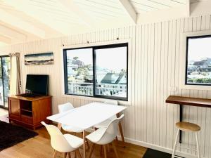 a white table and chairs in a room with windows at Sandy Beach Apartment in Russell