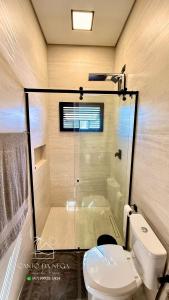 a bathroom with a glass shower and a toilet at Canto da Nega - Seu canto na Praia! in Itapoa