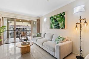 een woonkamer met een bank en een tafel bij Cairns 2BR Palms Stay Top Floor & Pool View in Westcourt