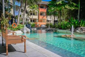 een zwembad in een resort met een bankje en een fontein bij Cairns 2BR Palms Stay Top Floor & Pool View in Westcourt