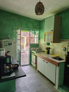 a kitchen with green walls and white cabinets and a sink at Casa Marco in Fray Bentos