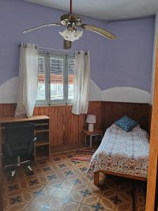 a bedroom with a bed and a desk and a ceiling fan at Casa Marco in Fray Bentos
