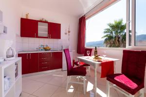 a kitchen with red cabinets and a table and a window at Apartments with parking space Stari Grad, Hvar - 8726 in Stari Grad