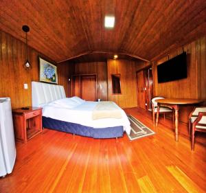 a bedroom with a bed and a table and a television at Pousada da Lua in Campos do Jordão
