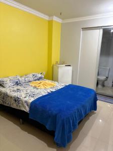 a bedroom with a bed with a blue blanket on it at Quarto próximo ao centro in Manaus
