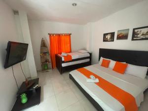 a bedroom with two beds and a television in it at Hotel Taganga Dive Santa Marta in Taganga