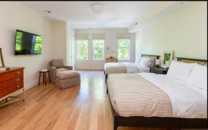 a bedroom with two beds and a tv and a chair at Massive NYC Brownstone with Patio in New York