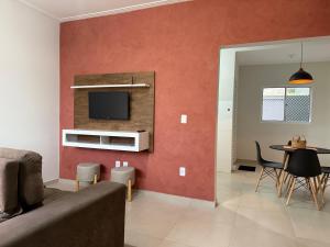 Una sala de estar con un sofá y un televisor en una pared. en Conforto a 8min da Canção Nova com Garagem, en Cachoeira Paulista