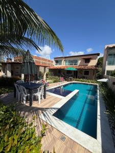 a pool with a table and chairs next to a building at Meu Aconchego in Tamandaré
