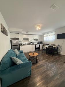 a living room with a blue couch and a kitchen at Charmant appartement au sous-sol in Longueuil +2 photos
