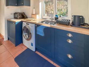 een blauwe keuken met een wasmachine en een wastafel bij Swinside Cottage in Ennerdale Bridge