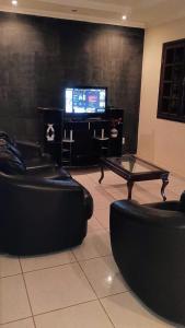 a living room with two black couches and a tv at Sítio vida boa - Jambreiro in Itabira