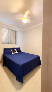 a bedroom with a blue bed and a ceiling fan at Apartamento em frente ao novo shopping in Ribeirão Preto