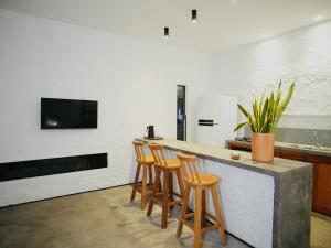 a kitchen with a bar with stools and a tv at Vilarejo Casa Branca in Barreirinhas