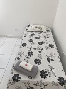a bed with a black and white blanket with a towel at Apartamento dois quartos acolhedor prox Hospital Regional e Rodoviária in Santo Antônio de Jesus