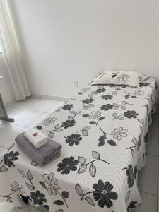 a bed with a black and white blanket with flowers on it at Apartamento dois quartos acolhedor prox Hospital Regional e Rodoviária in Santo Antônio de Jesus +29 photos